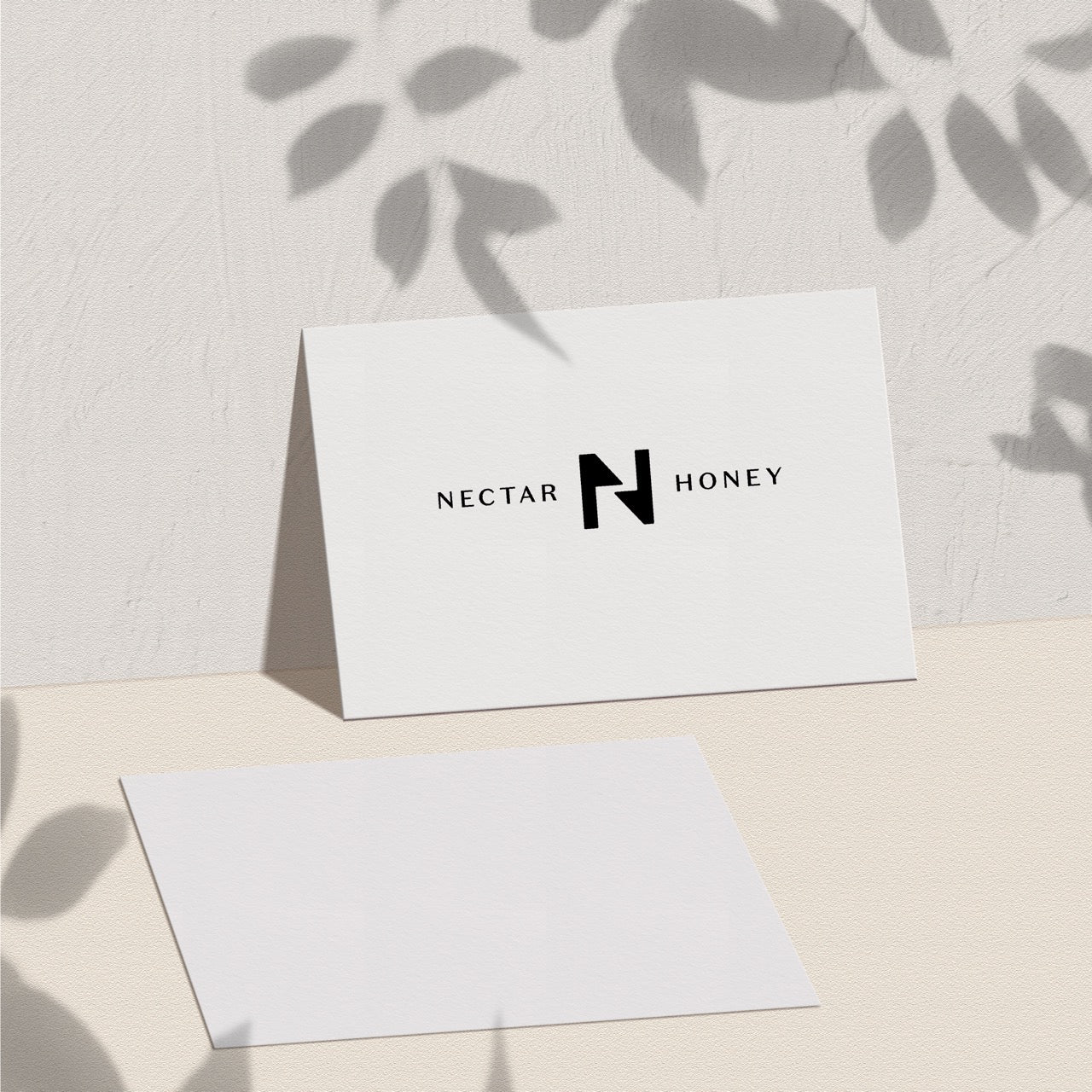 A physical gift card with the Nectar Honey logo placed on a surface with a shadow of leaves overhead.